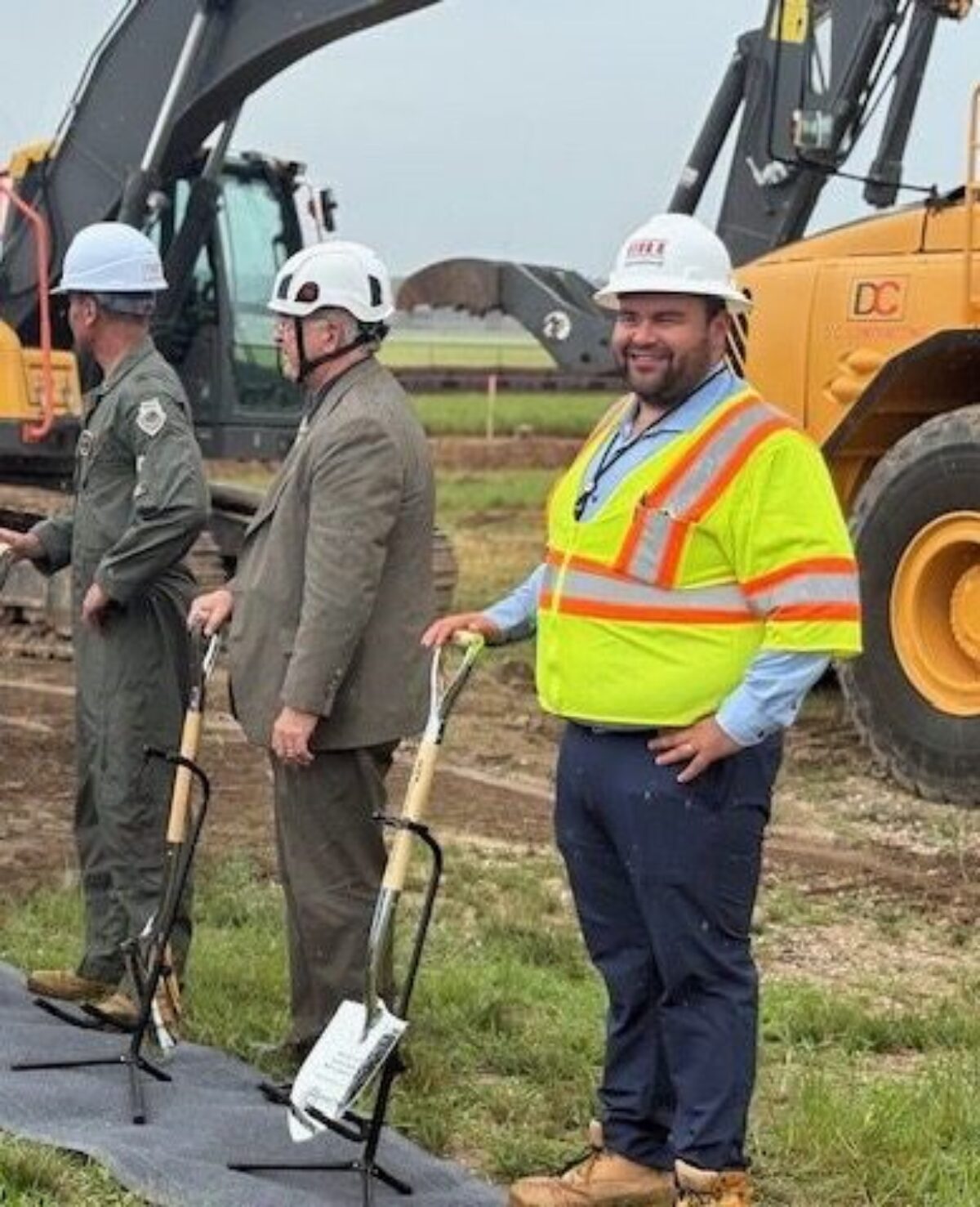 A group of people with white hard hats and ceremonial shovels lined up and posed for a picture
