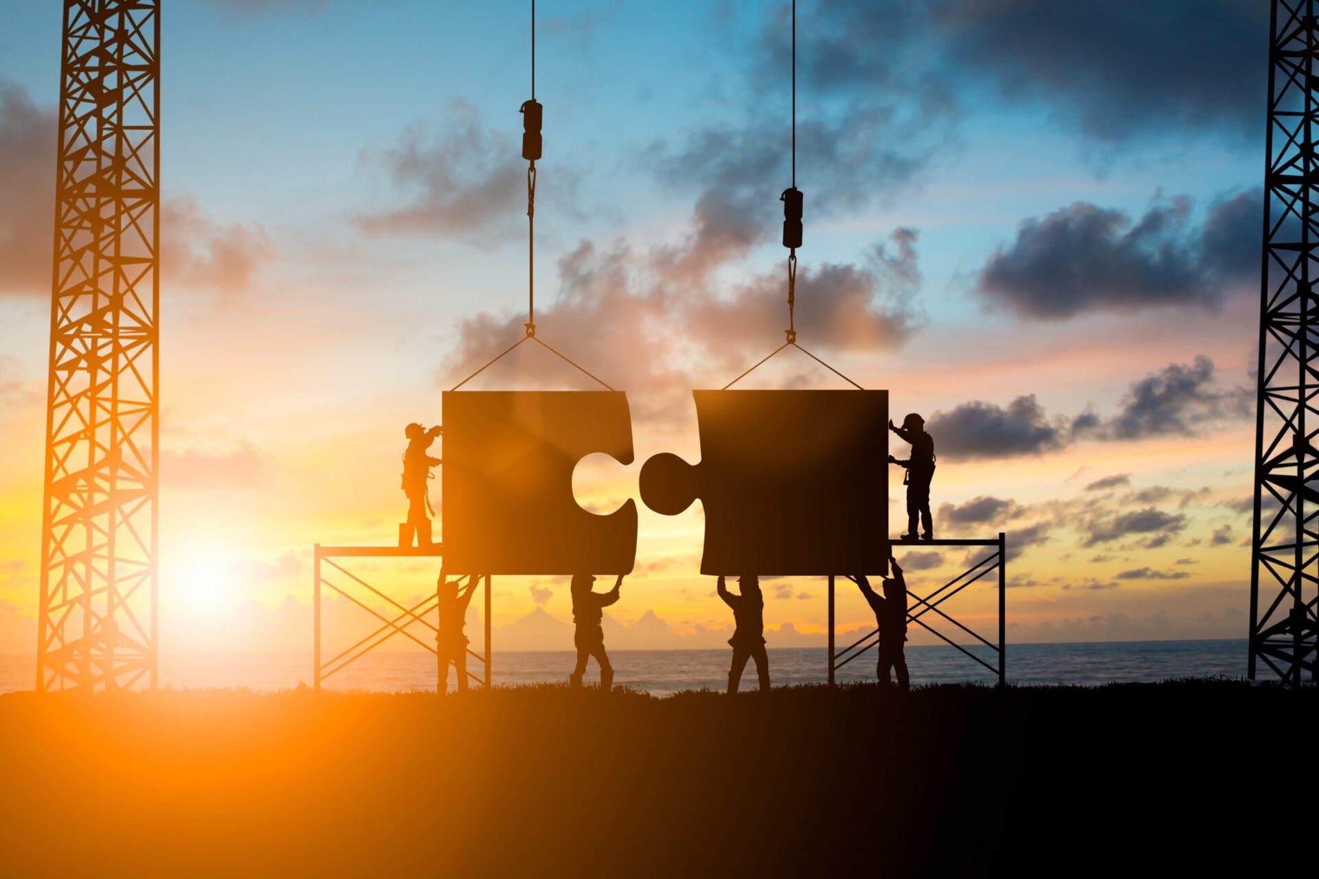 Silhouette of a team working together to put puzzle pieces together